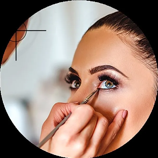Une maquilleuse applique de l’eye-liner au pinceau sur l’œil d’une jeune femme.