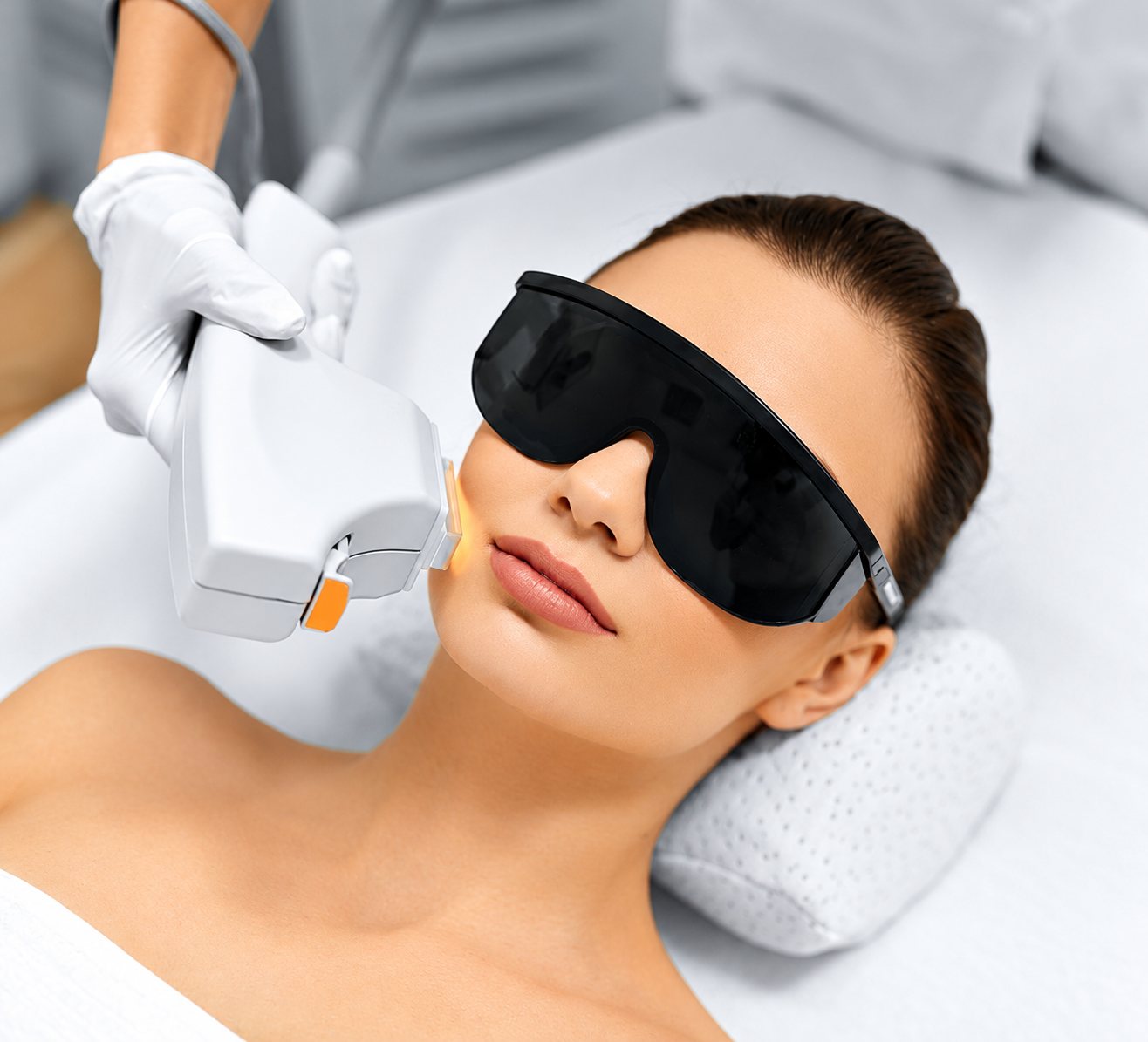 Femme portant des lunettes de protection pendant un traitement laser du visage.