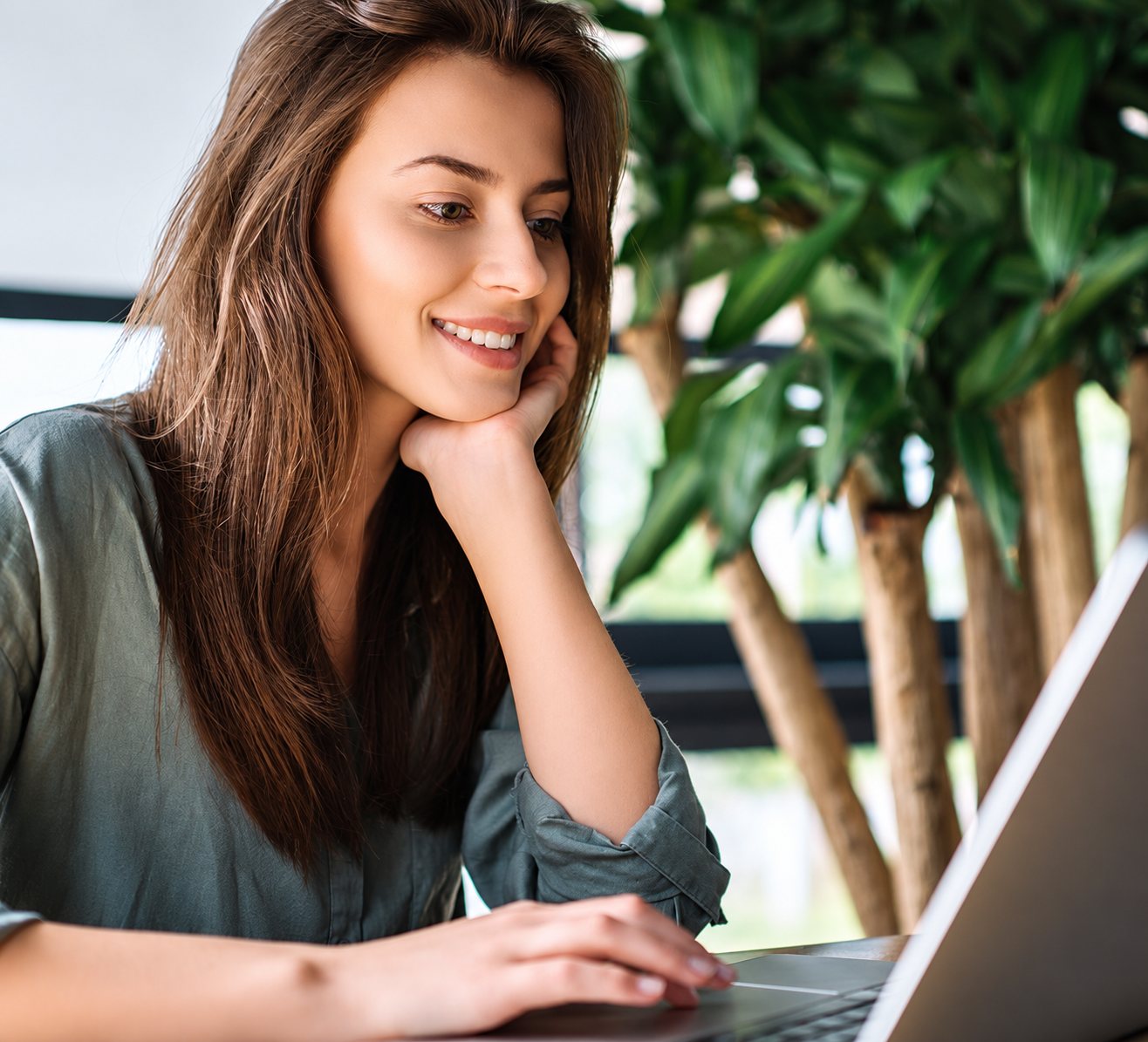 Jeune femme souriante devant un ordinateur portable.