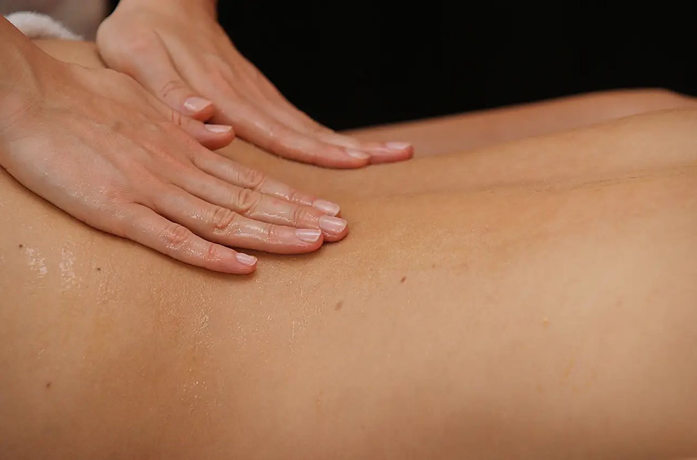 Une masseuse masse à l’huile le dos d’un client.