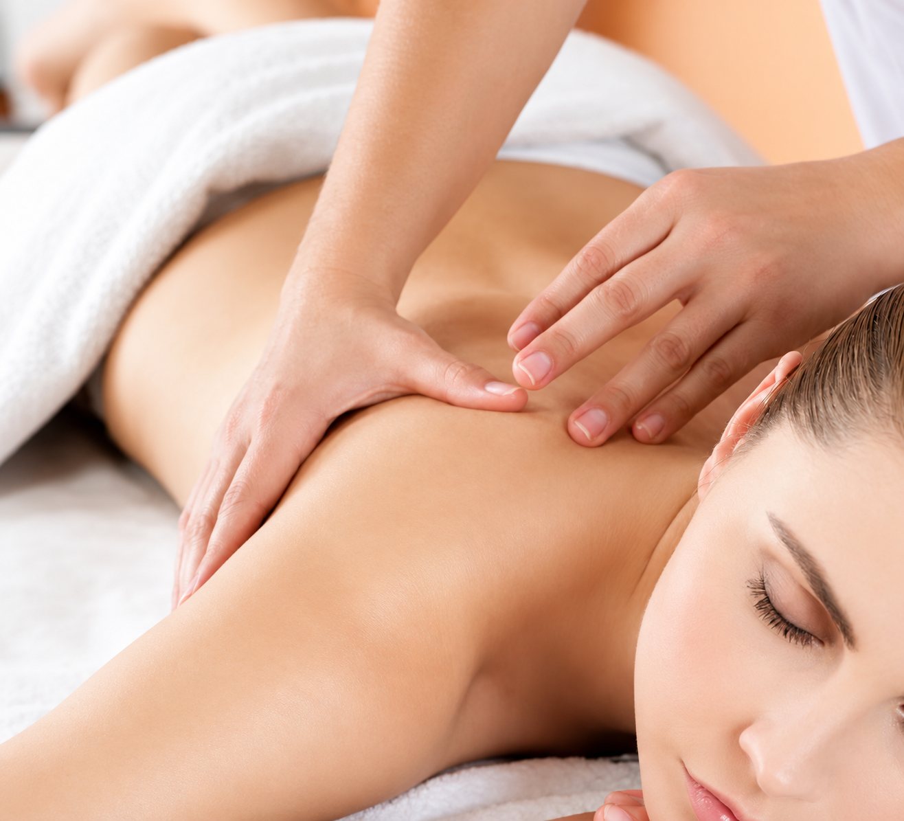 Femme allongée, les yeux fermés, pendant un massage du dos.