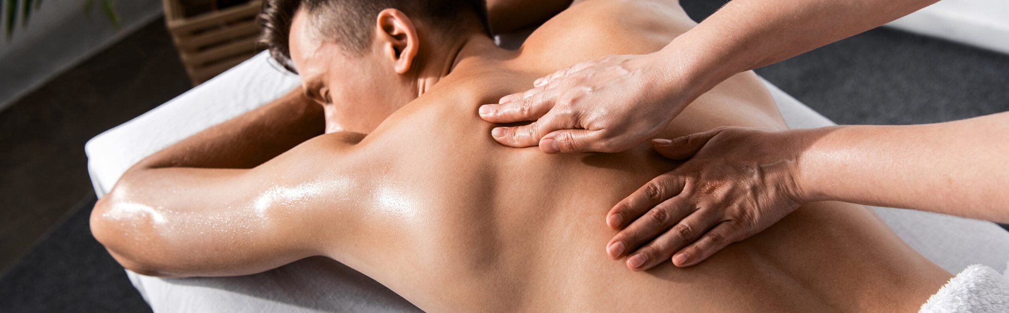 Massage du dos d’un homme à l’huile sur une table de massage.