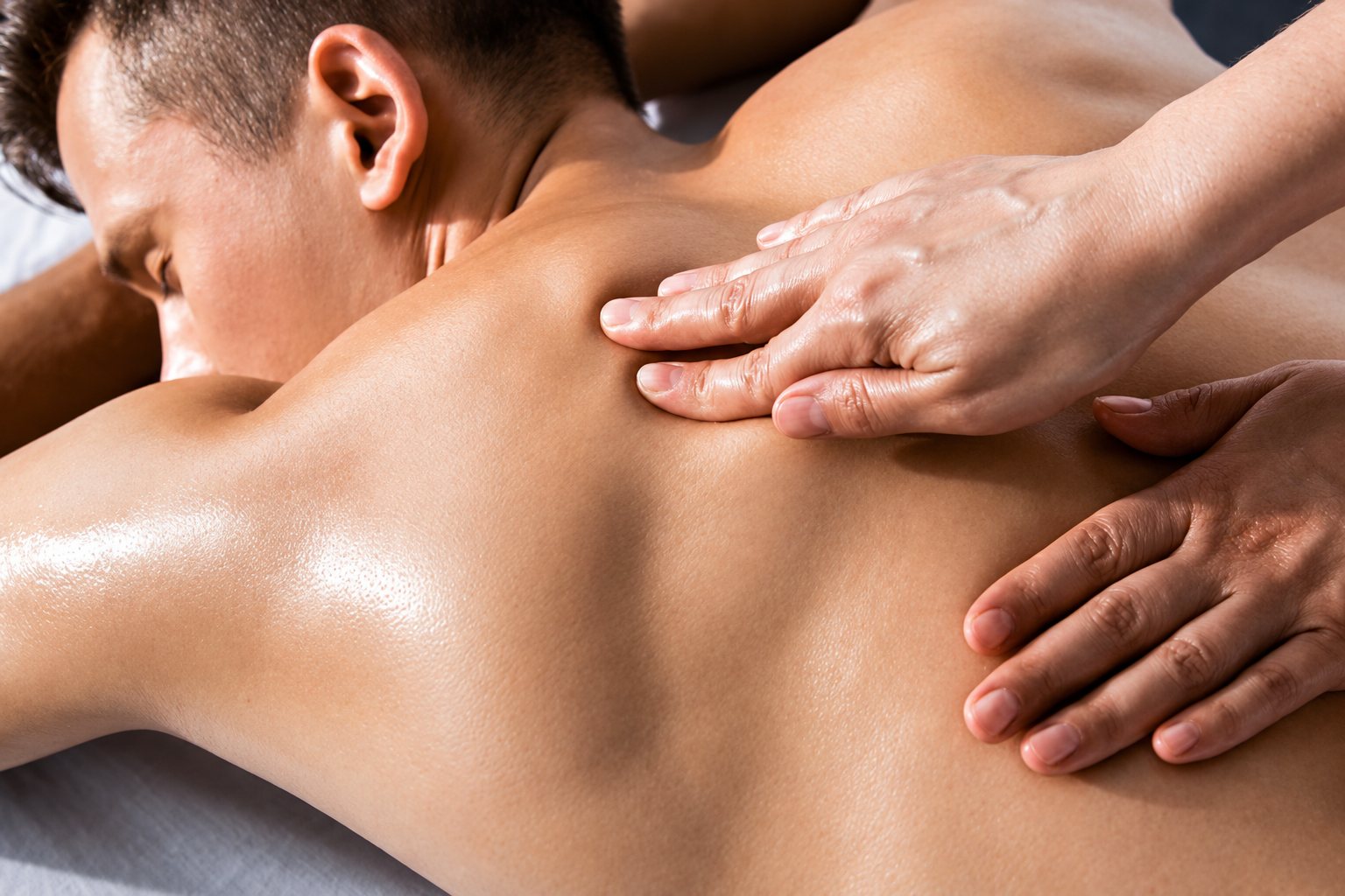 Client allongé recevant un massage du dos à l’huile.