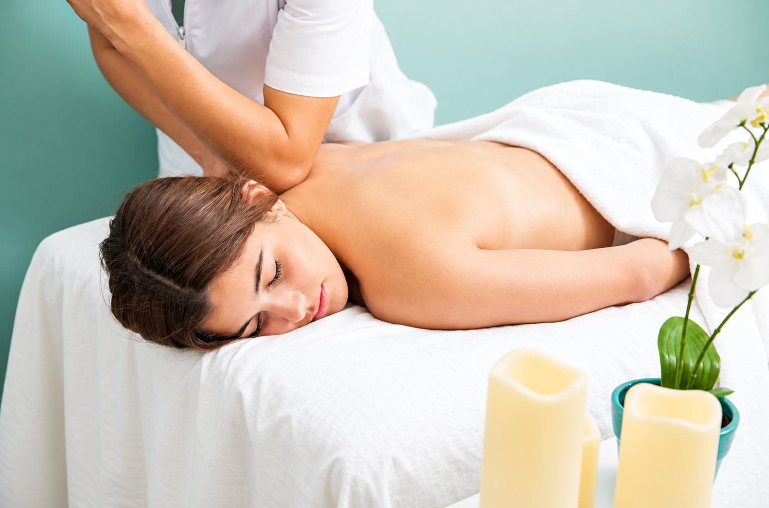 Massage du dos d’une femme dans une cabine de spa aux bougies.
