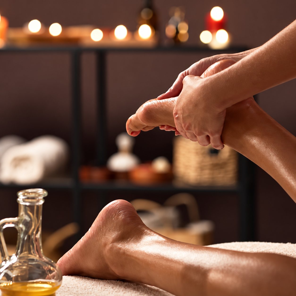 Massage des pieds à l’huile, bougies en arrière-plan.