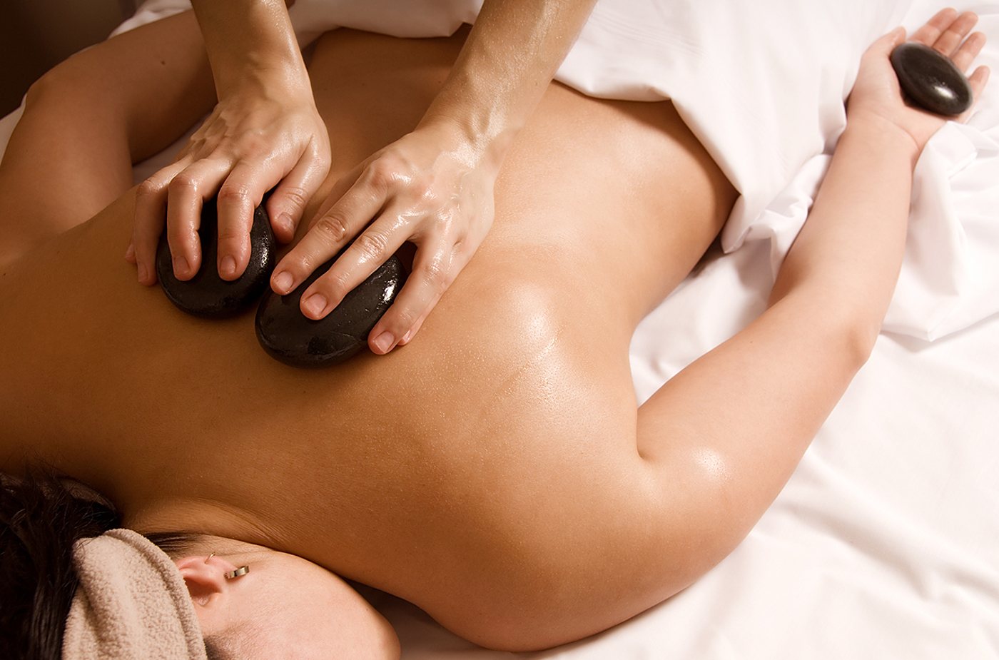 Massage du dos avec des pierres volcaniques chaudes dans un spa.